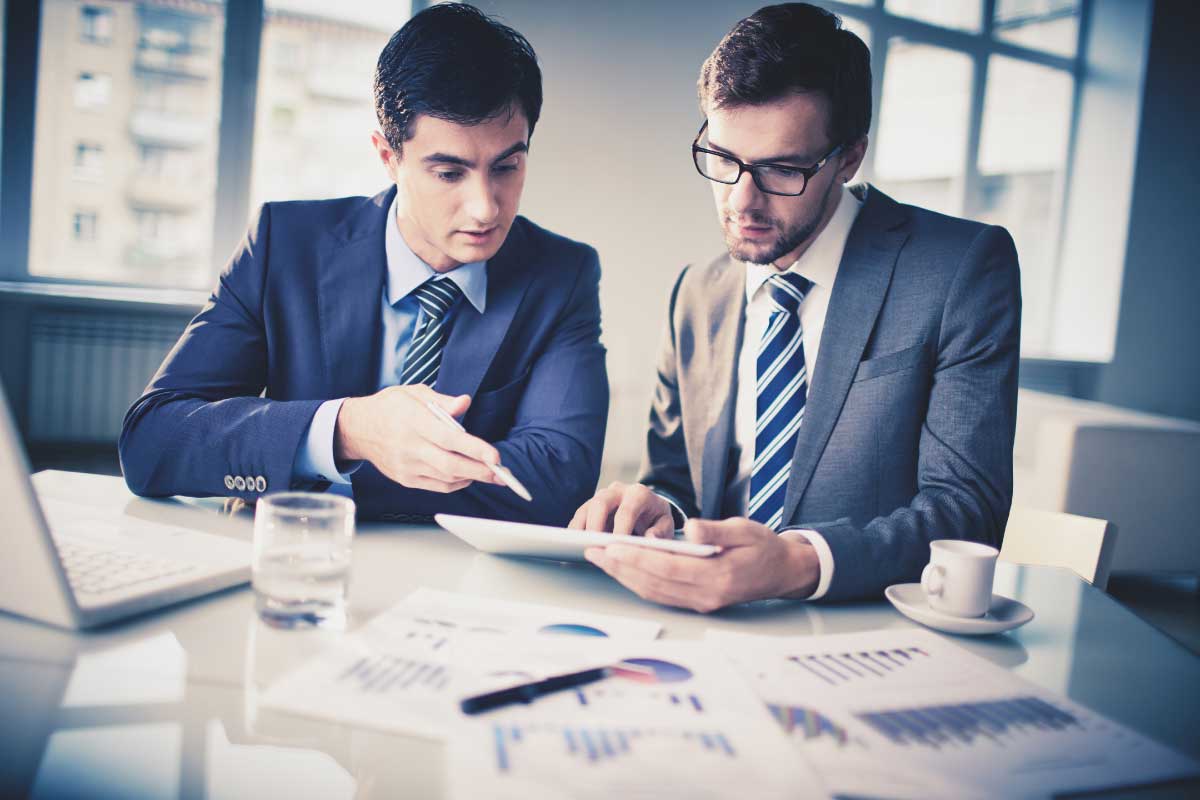 Dos hombres de negocios analizando información en una tableta electrónica.