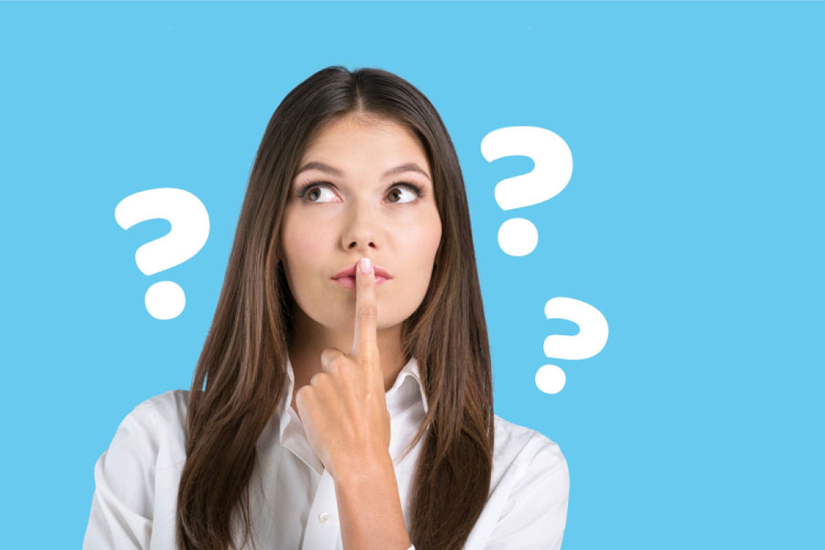 Mujer con un dedo en su boca y signos de interrogación a su alrededor