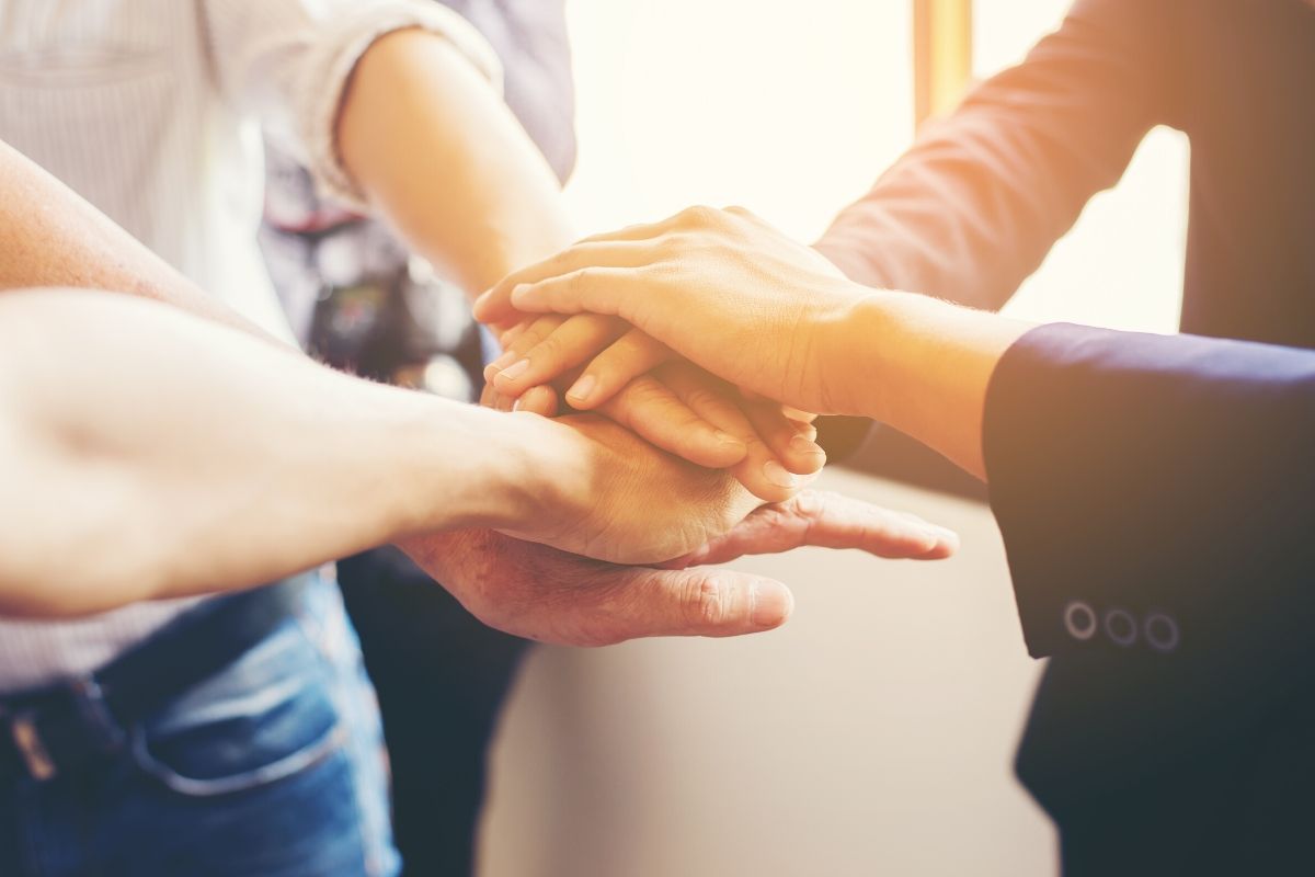 Acercamiento de un grupo de cuatro personas poniendo las manos juntas, una sobre otra.