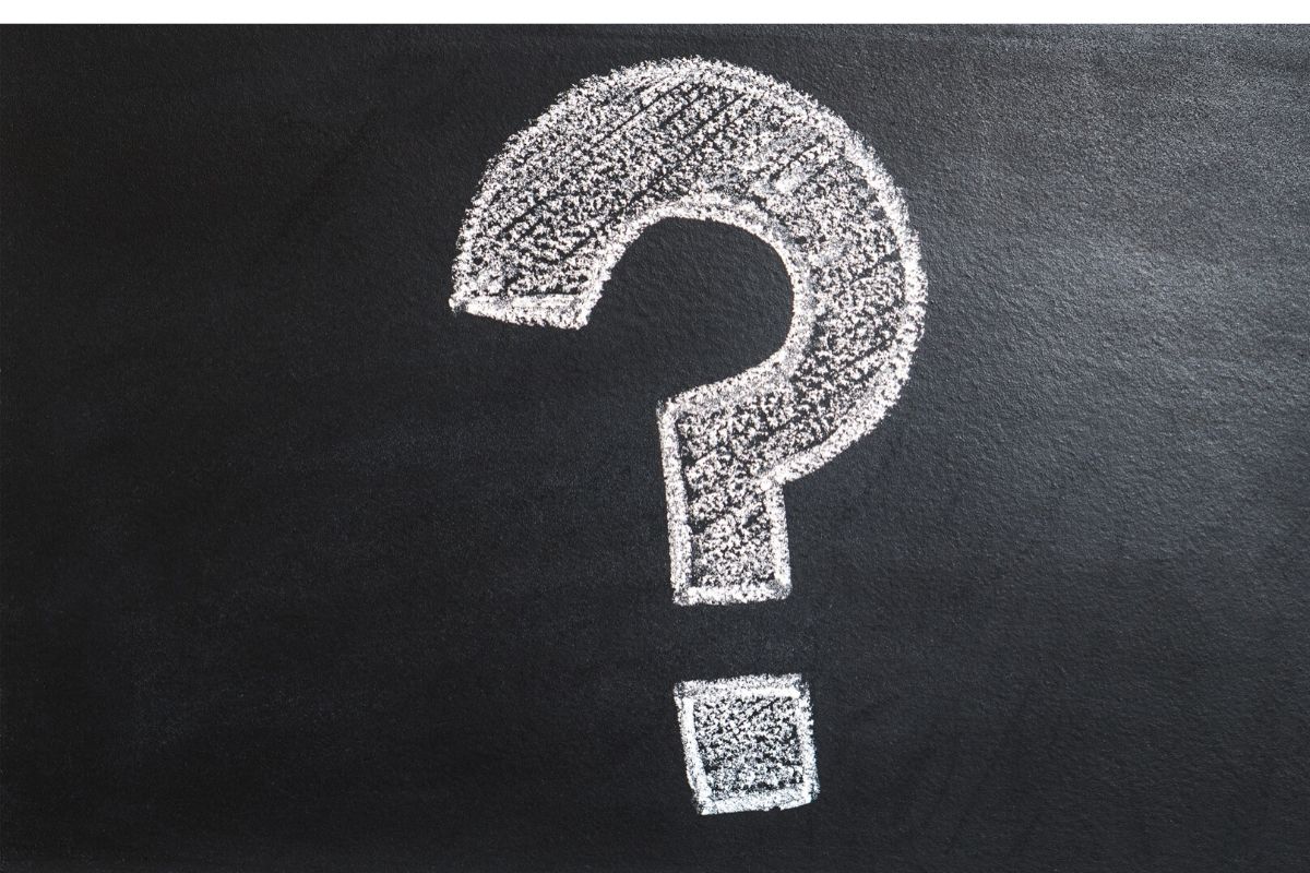 Toma superior de un signo de interrogación dibujado con tiza sobre un tablero negro.