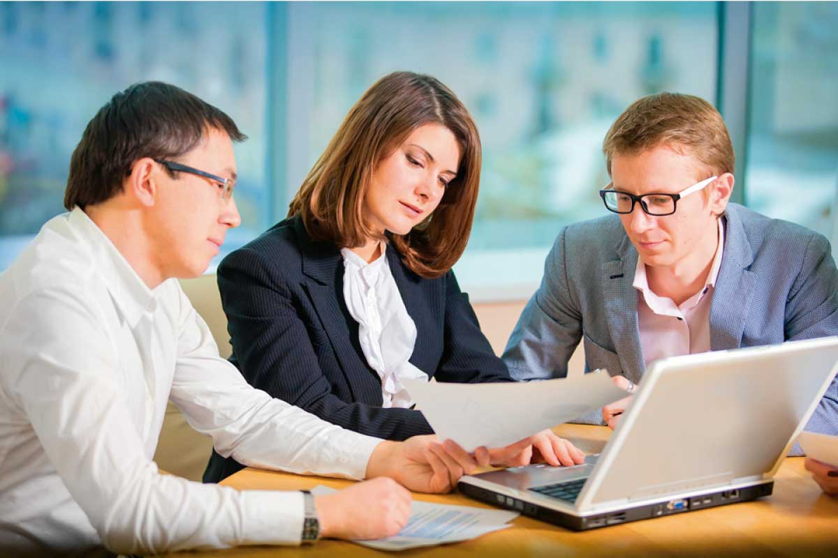 Dos hombres y una mujer sobre una mesa en una reunión