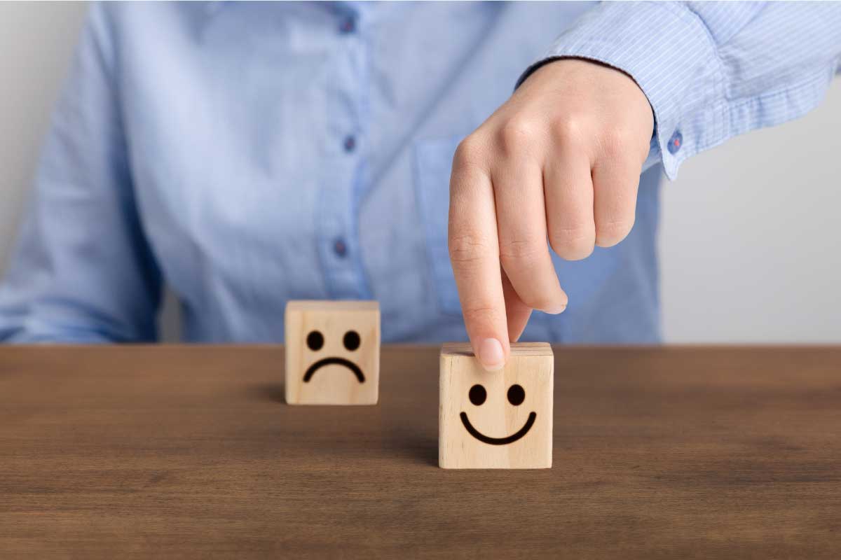 Persona escogiendo un cubo que tiene un emoji de una cara feliz sobre el que tiene la cara triste