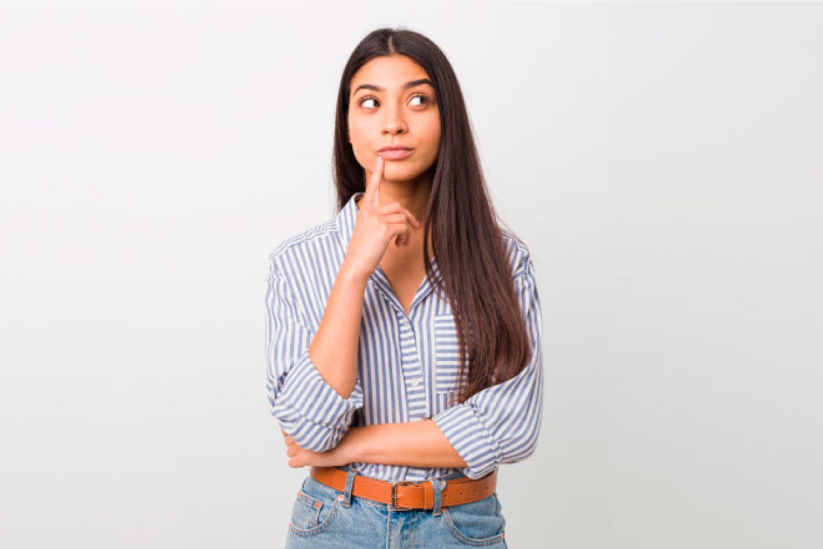 Mujer joven con el dedo índice sobre los labios, mirando hacia la derecha y pensando