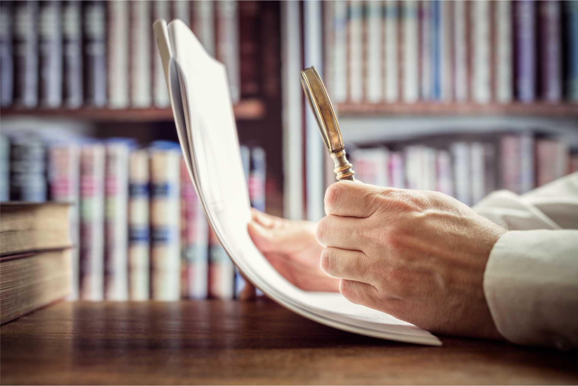 Hombre inspeccionando un documento con una lupa.