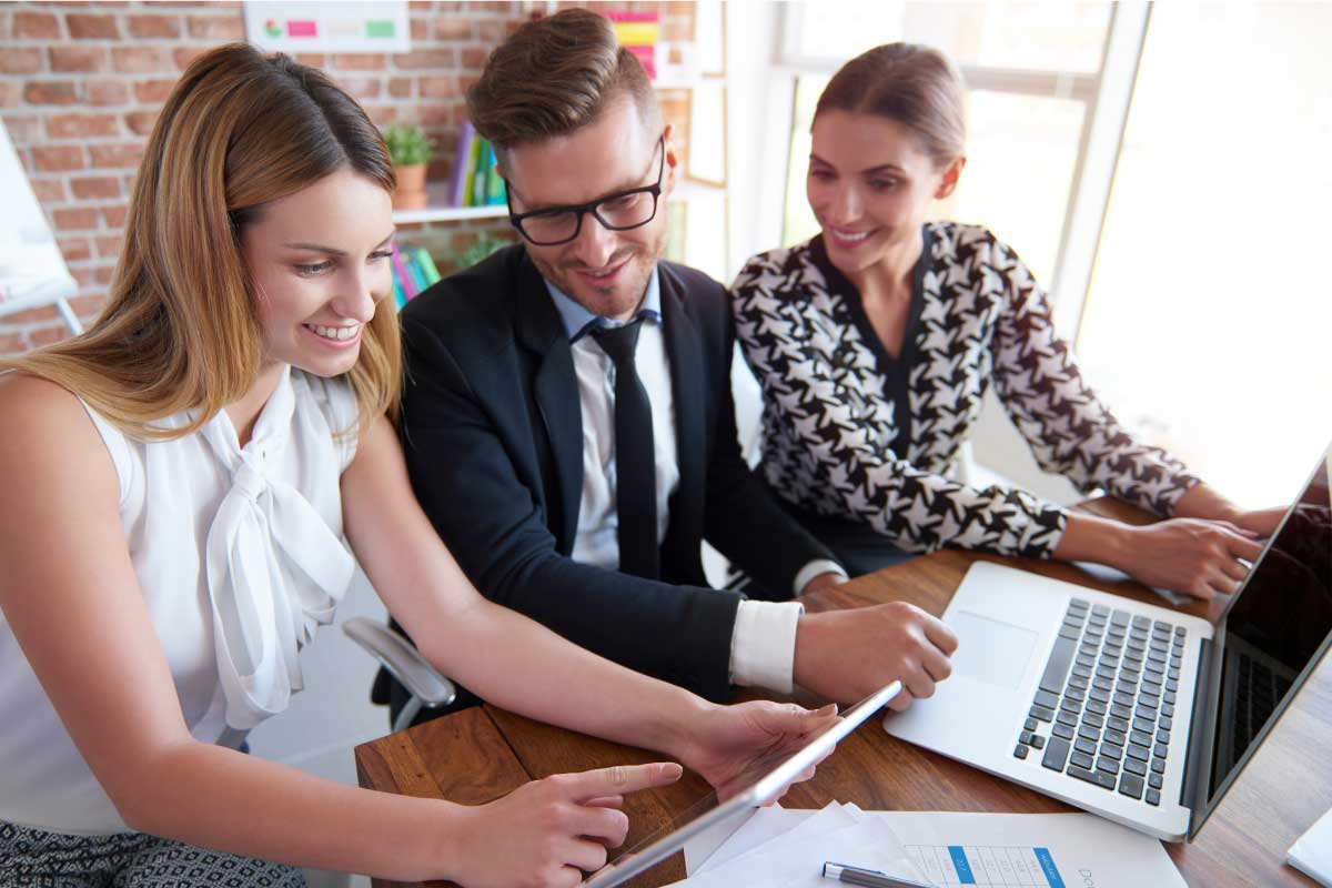 Tres compañeros de oficina analizando información en una tablet
