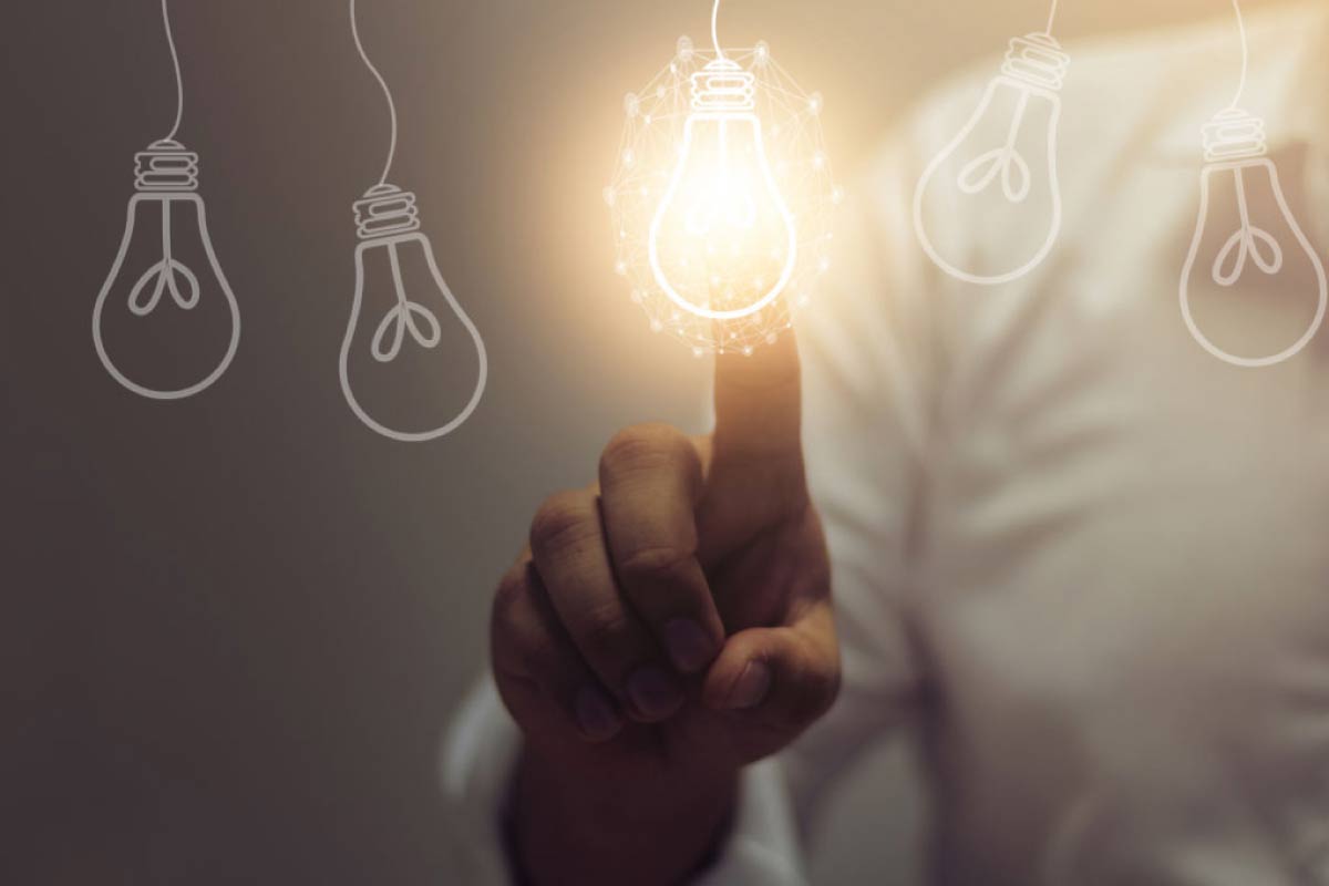 Acercamiento de la mano de un hombre tocando la imagen de una bombilla y prendiéndola