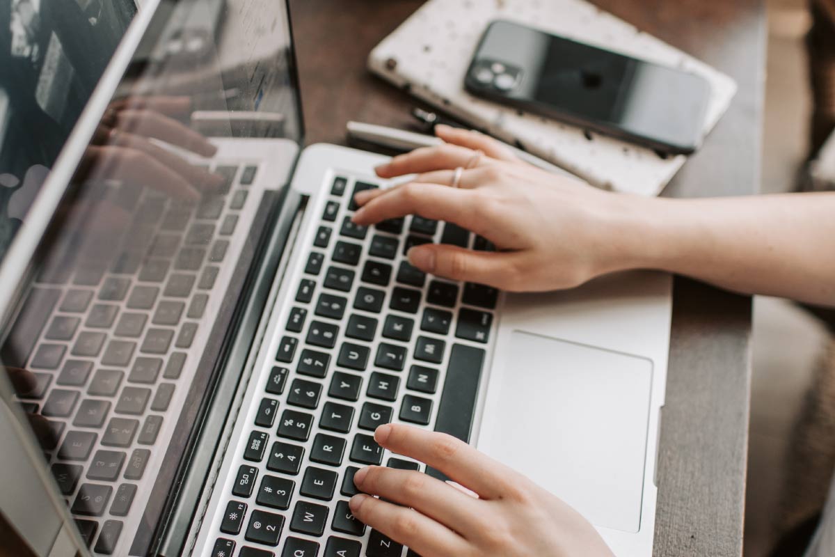 Acercamiento de las manos de una mujer escribiendo en un computador portatil.
