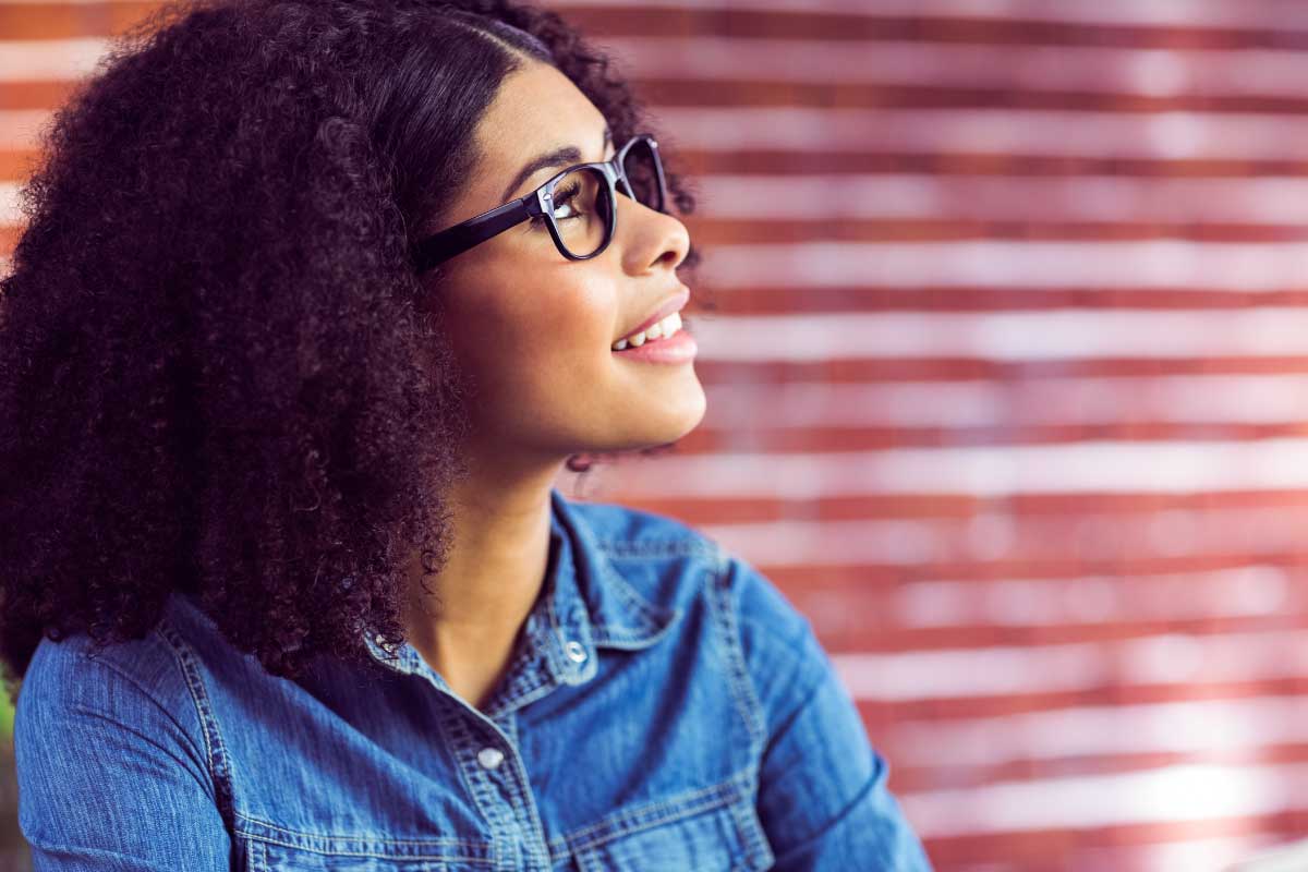 Mujer joven mirando hacia arriba, pensando y sonriendo