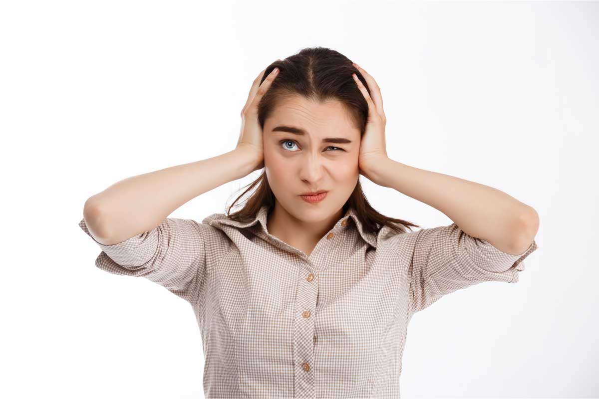 Mujer tapando sus orejas con las manos en signo de preocupación.