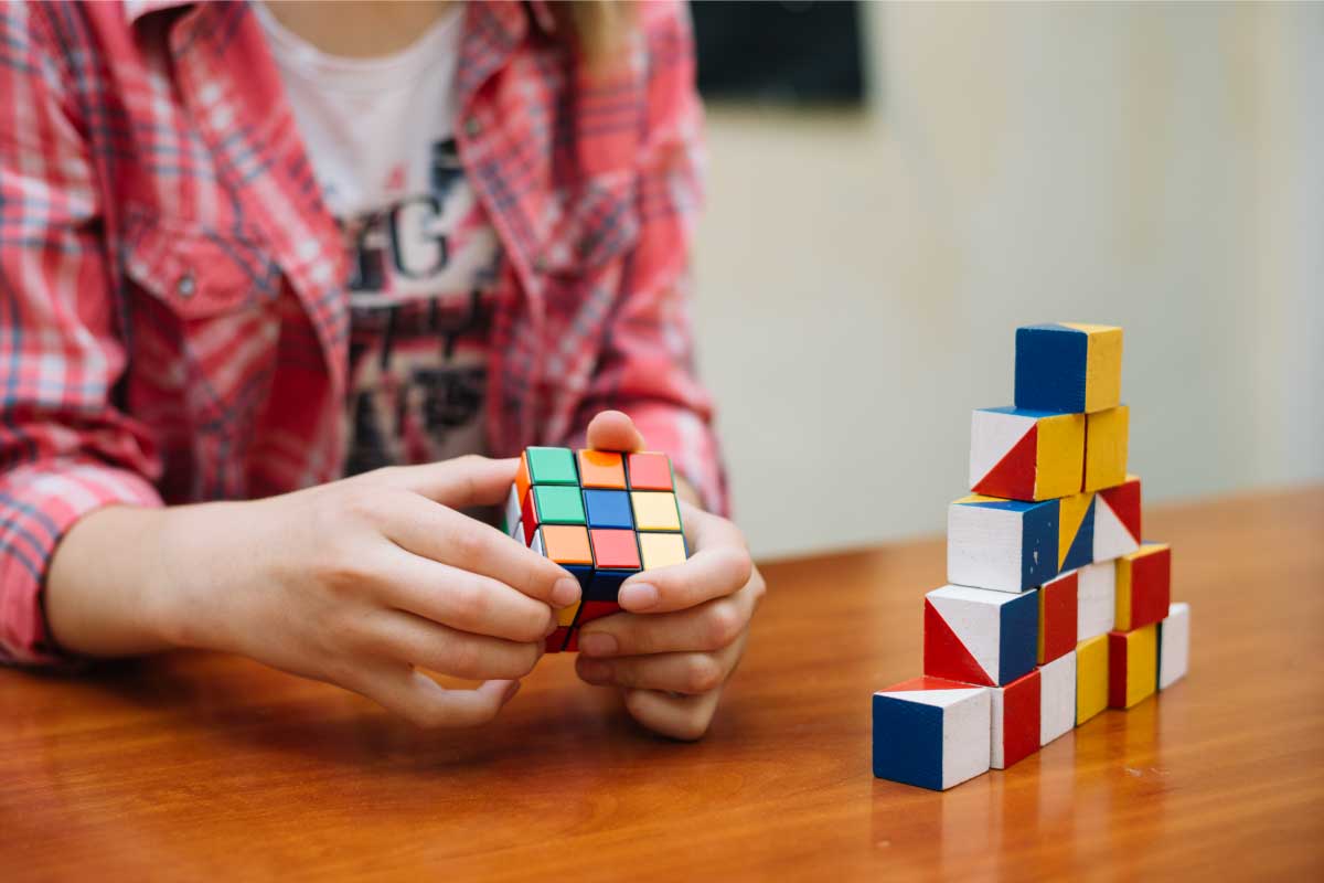 Acercamiento de una persona sosteniendo en sus manos un cubo de Rubik, tratando de resolverlo.