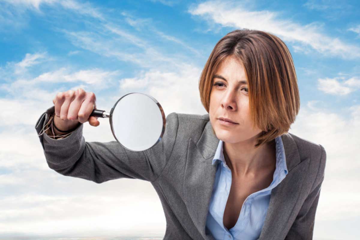 Mujer joven de negocios mirando a través de una lupa.