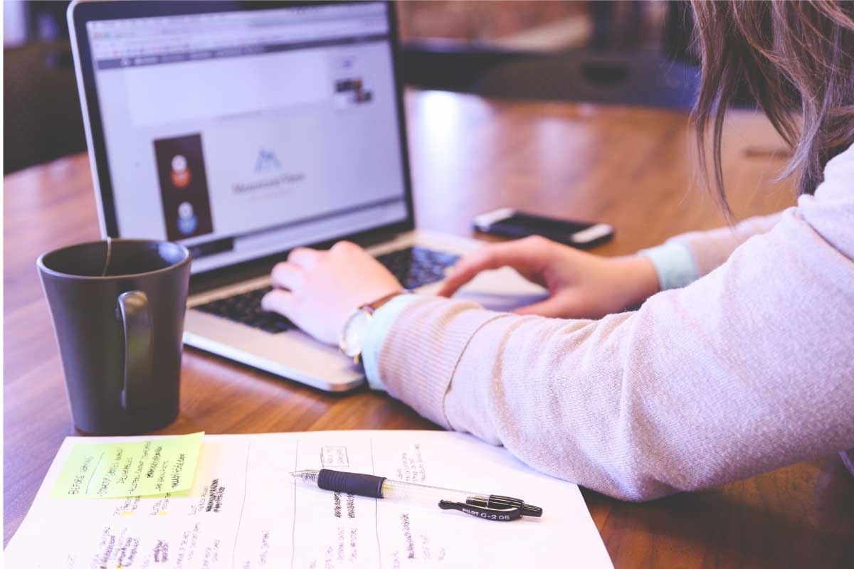 Persona sentada en un escritorio, escribiendo en un computador portable.