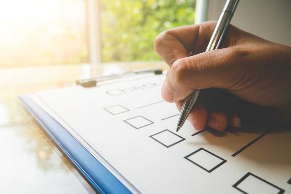 Acercamiento de la mano de una persona marcando opciones en una lista de chequeo.