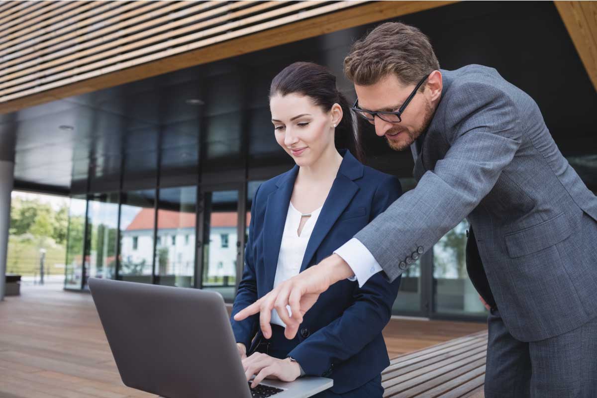Mujer joven ejecutiva escribiendo en un computador portatil en exteriores.