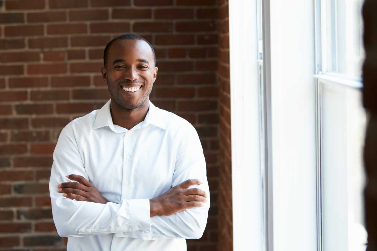 Hombre joven con los brazos cruzados y la cara sonriente.
