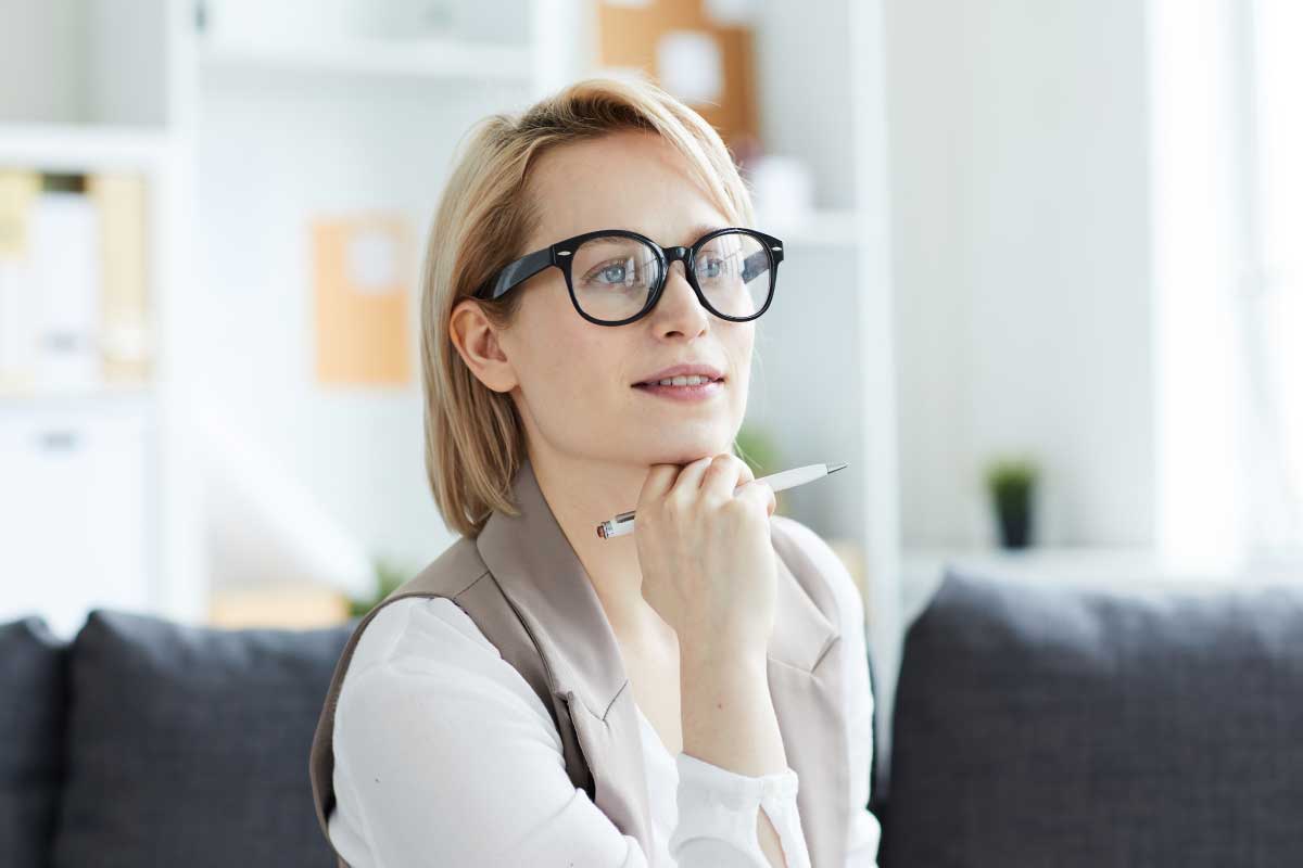 Mujer joven ejecutiva con la mano sobre su mentón, sosteniendo un lapicero.