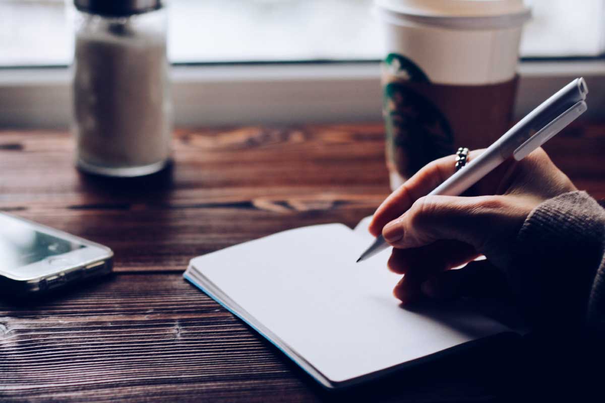 Acercamiento de la mano de una mujer escribiendo en una libreta.