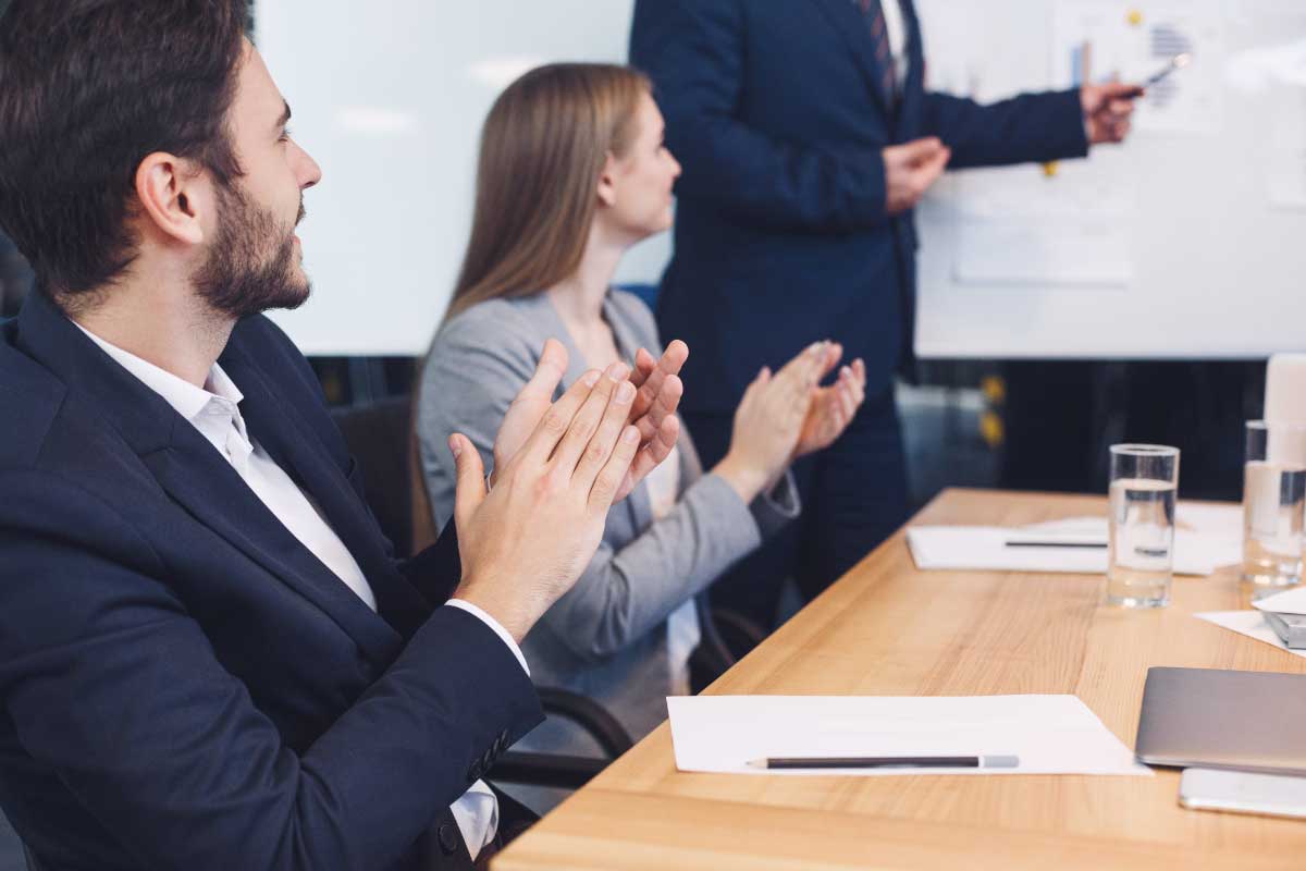 Grupo de personas en una conferencia de negocios aplaudiendo al expositor.