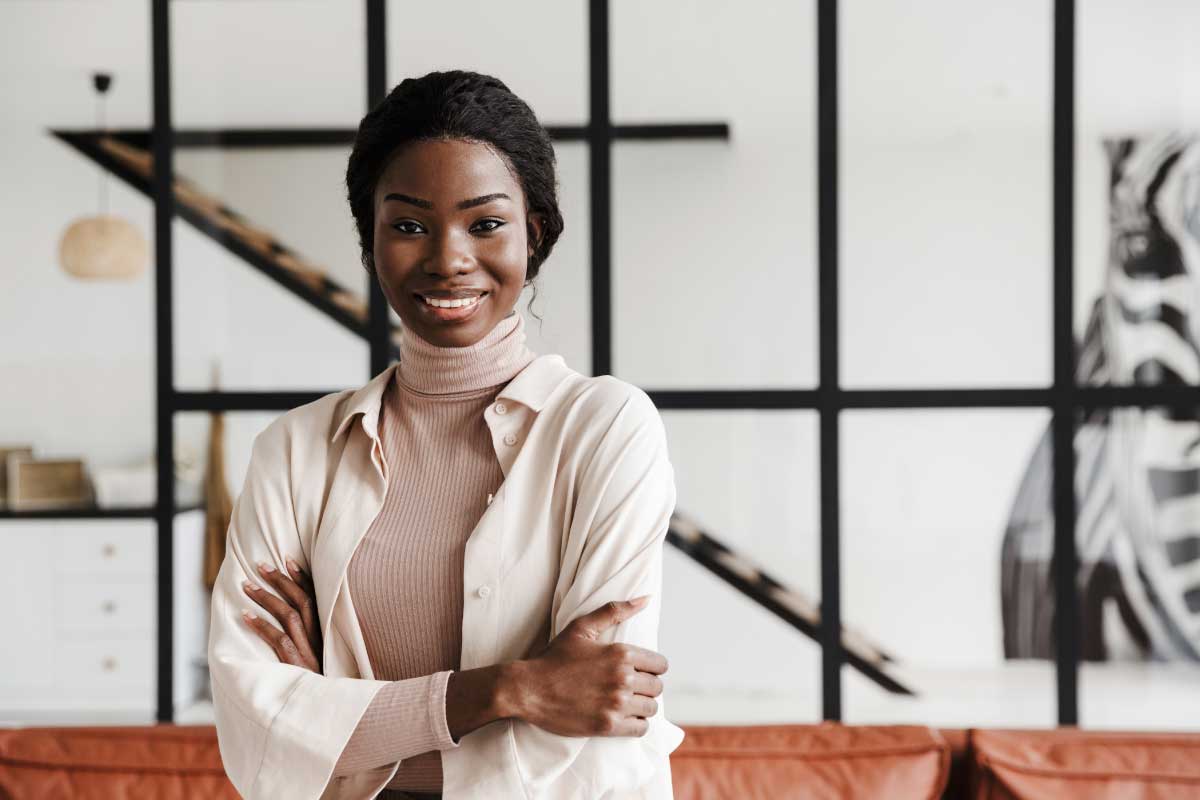 Mujer joven mirando la cámara con los brazos cruzados y sonriendo.
