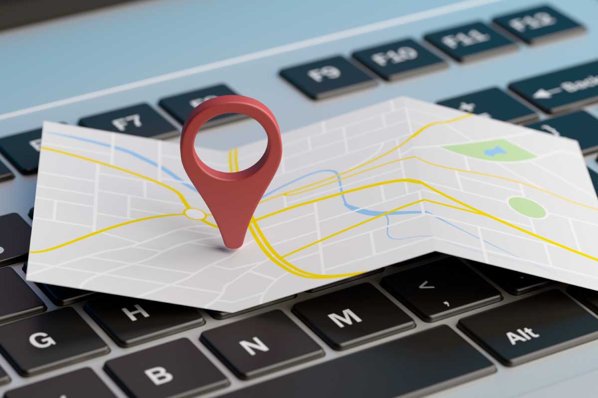 Acercamiento de un teclado de computador sobre el cual hay un mapa con un marcador.