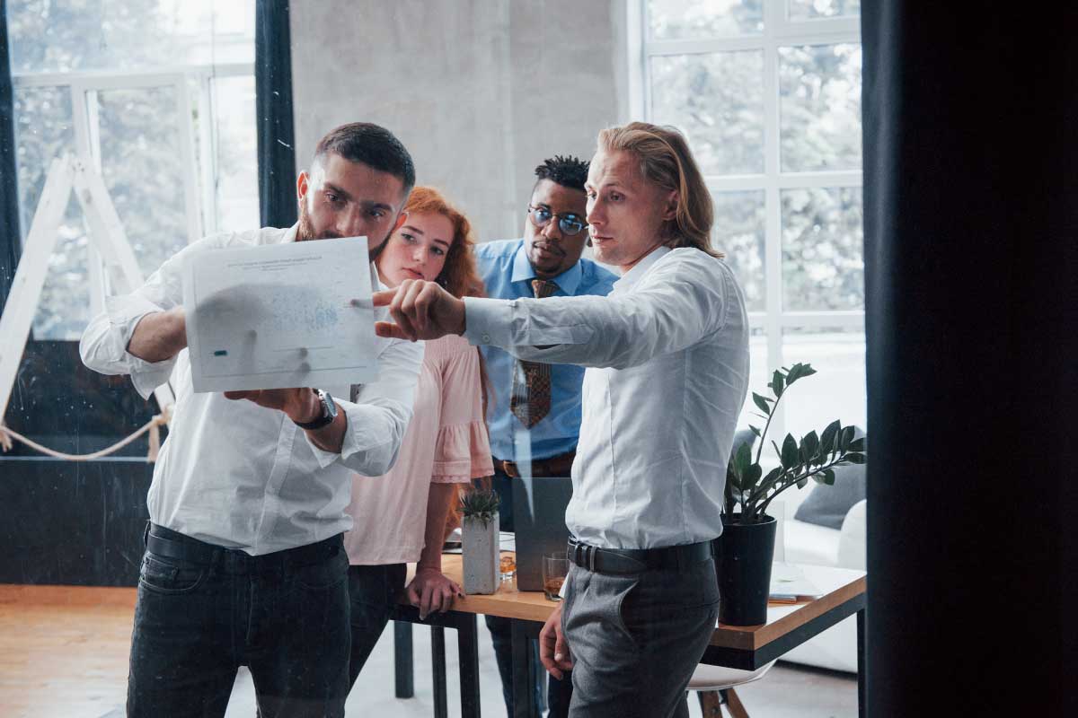 Grupo de personas en una oficina observando un documento que uno de ellos sostiene. a nivel de los ojos, en el aire.