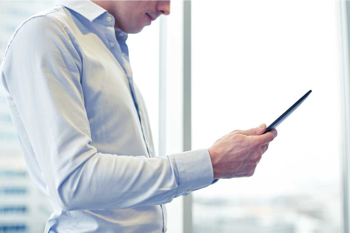 Hombre de negocios sosteniendo y mirando una tableta.