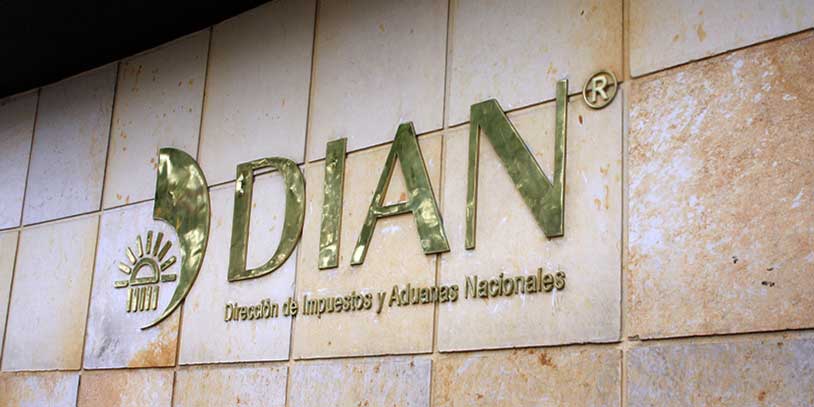 Fotografía del logo de la DIAN en material dorado sobre una pared de baldosas.