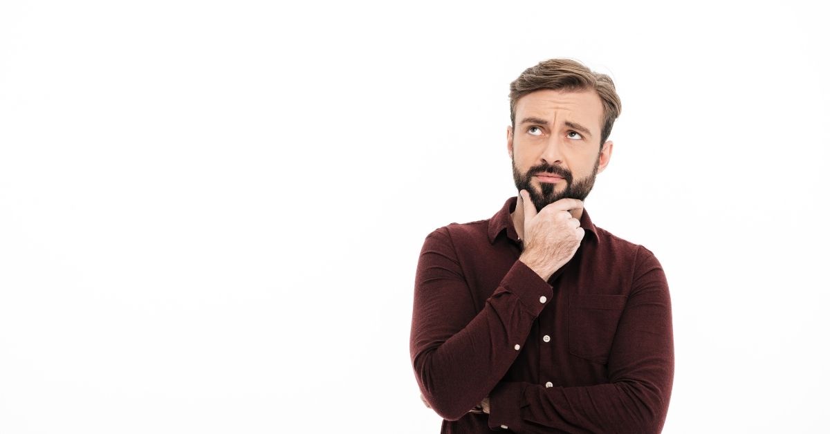 Hombre pensando con una mano sobre su barbilla.