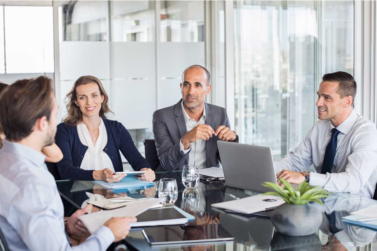 Grupo de personas en una oficina, sentadas al rededor de una mesa con documentos, en una reunión de negocios.