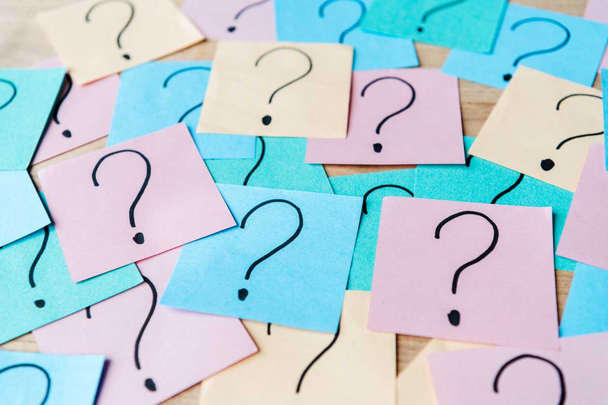 Conjunto de notas post-it con el signo de interrogación, esparcidas sobre una mesa.