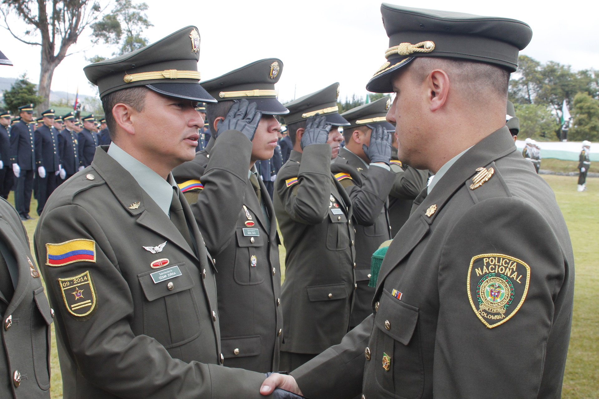 Grupo de policías en una ceremonia, uno de ellos saludando a un superior de mano.