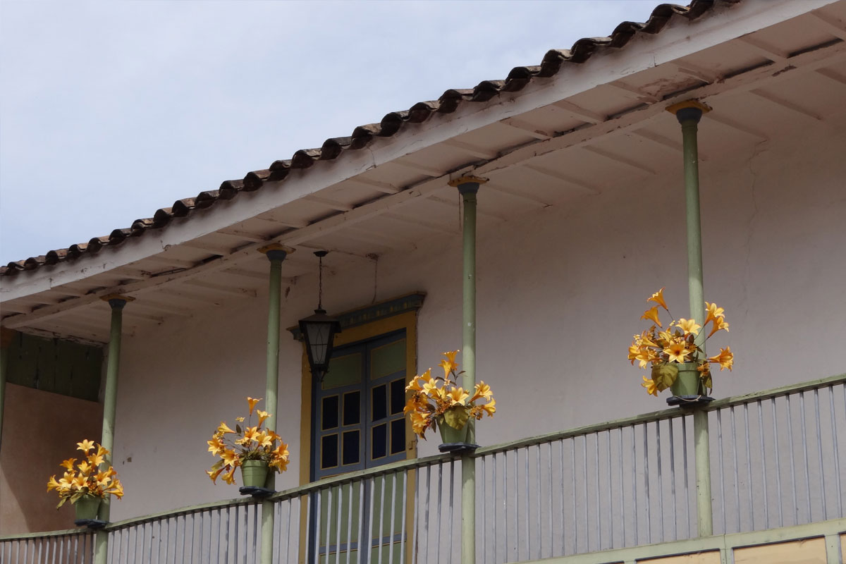 Balcón de casa estilo colonial con flores amarillas en Marinilla, Antioquia
