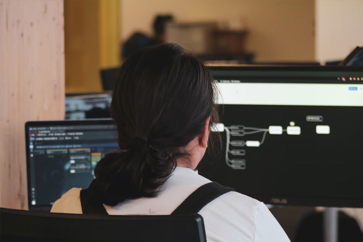 Estudiante de universidad, dando la espalda, en sala de computadores programando software