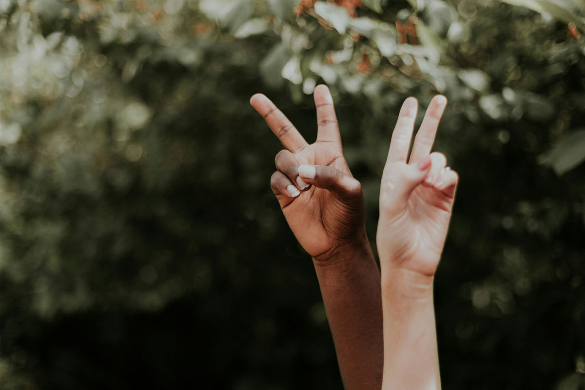 Dos manos levantadas formando una v con los dedos índice y medio
