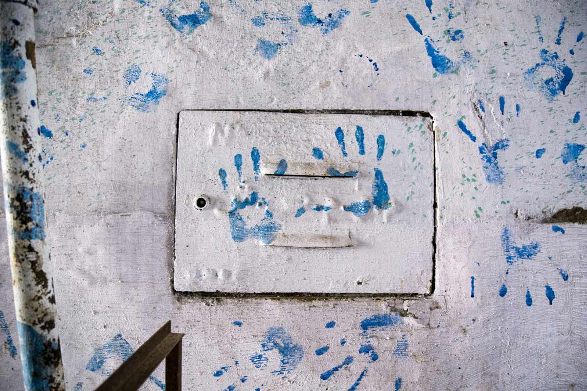 Pared blanca con varias impresiones de palmas de mano de color azul