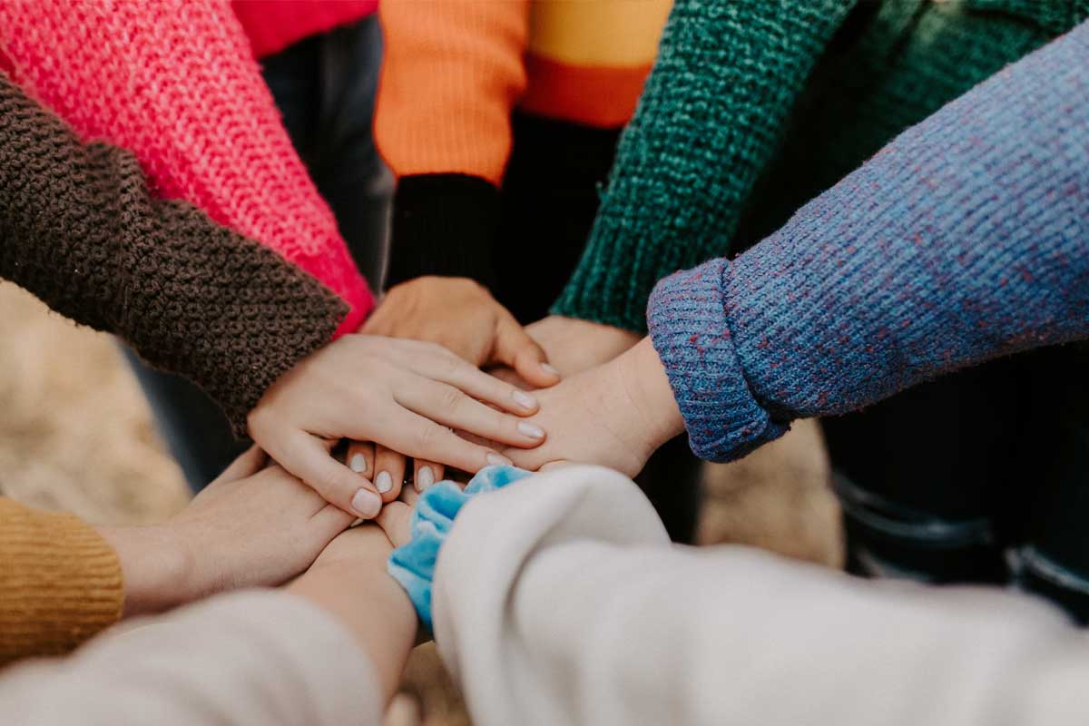 Grupo de personas uniendo sus manos como símbolo de unión.